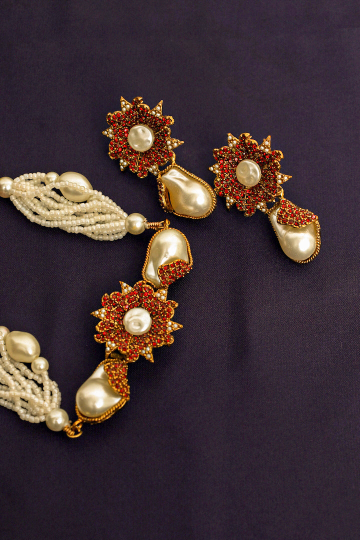 Ornate earrings with floral designs and pearl-like beads on a dark background