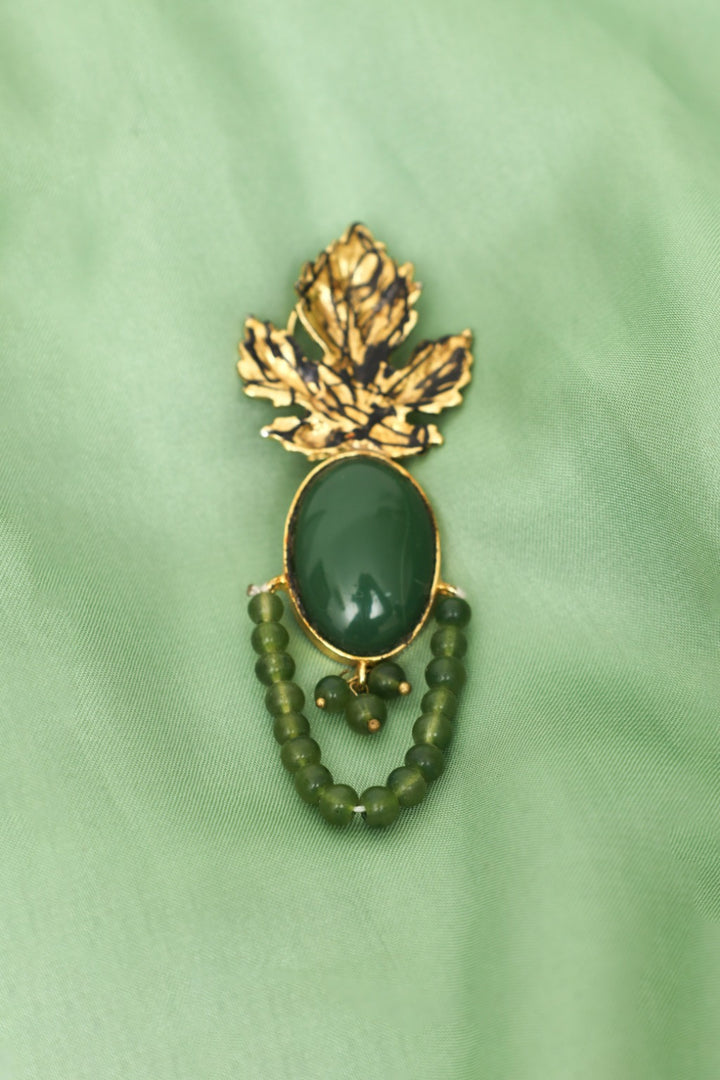 Jewelry with green stone and gold leaf design on a green background