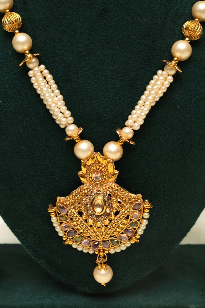 Gold necklace with pearl beads on a green background