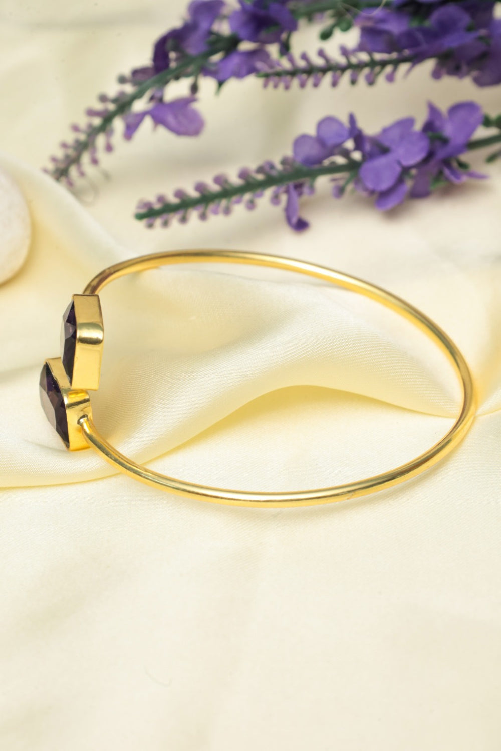 zehnaz gold tone bracelet on a beige fabric background with purple flowers